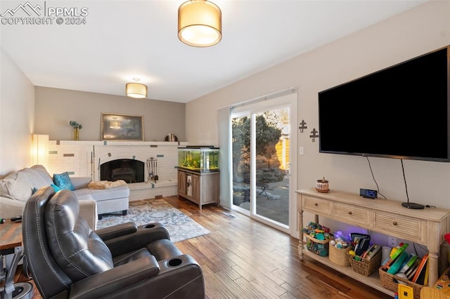 living room with hardwood / wood-style floors and a brick fireplace