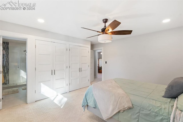 carpeted bedroom with connected bathroom, ceiling fan, and two closets