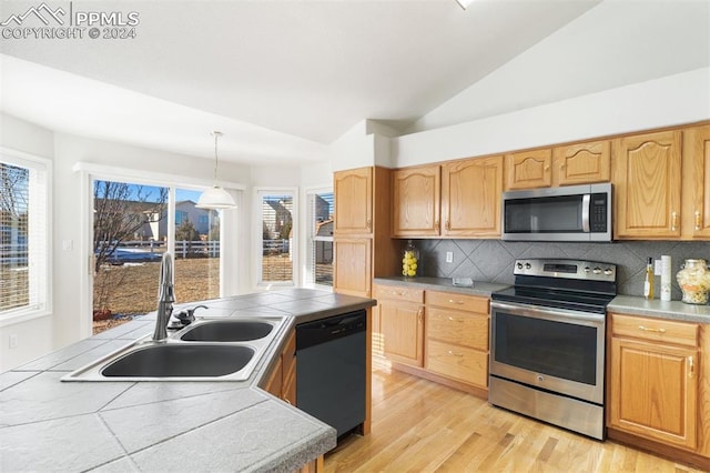 kitchen featuring tasteful backsplash, stainless steel appliances, vaulted ceiling, sink, and pendant lighting