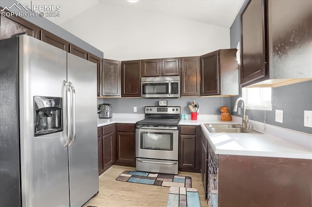 kitchen with dark brown cabinetry, sink, vaulted ceiling, appliances with stainless steel finishes, and light wood-type flooring