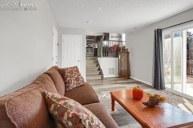 living room with light wood-type flooring and a textured ceiling