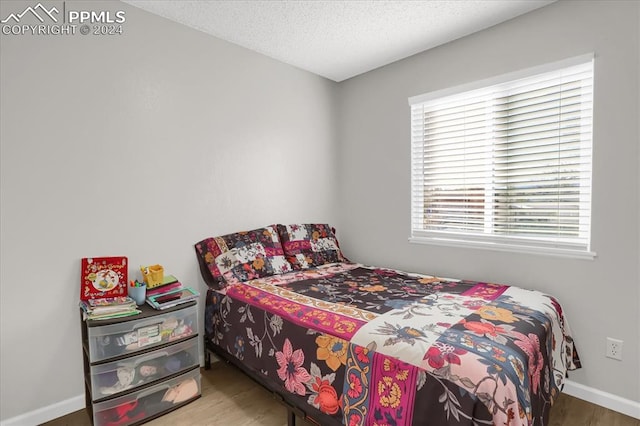 bedroom with a textured ceiling and hardwood / wood-style flooring