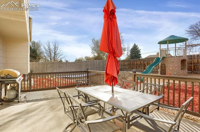 wooden deck with a playground and a grill