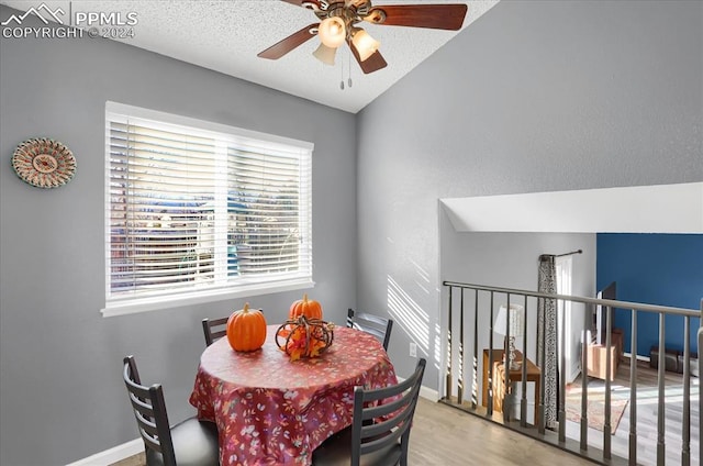 dining room featuring hardwood / wood-style flooring, ceiling fan, lofted ceiling, and a textured ceiling