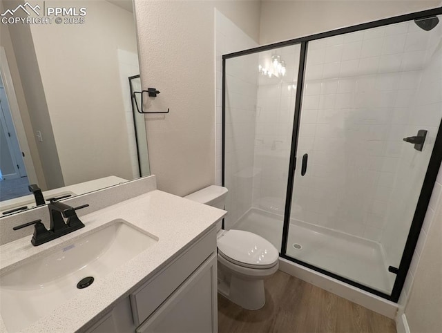 bathroom featuring a shower with shower door, toilet, wood-type flooring, and vanity