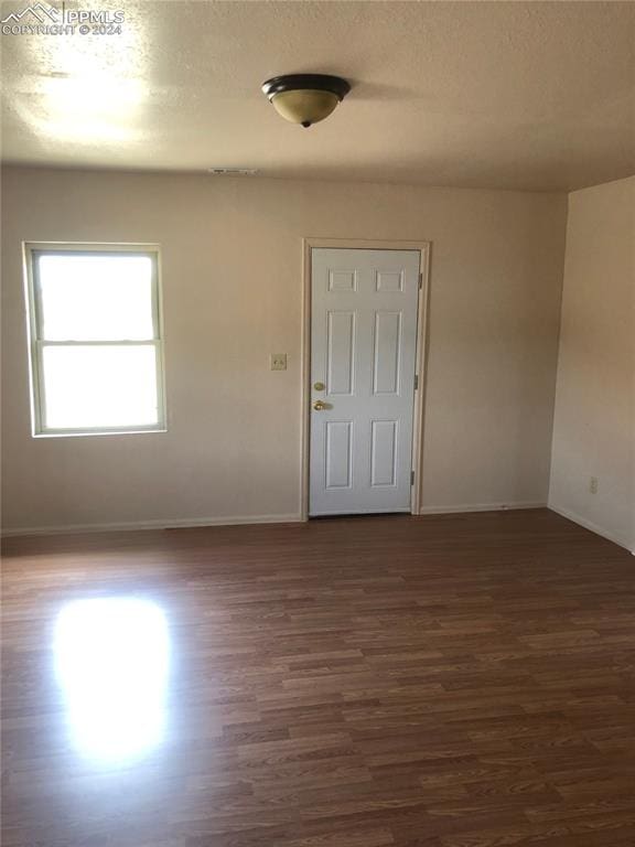 empty room with a textured ceiling and dark wood-type flooring