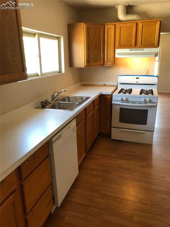 kitchen featuring white appliances, dark wood-type flooring, and sink