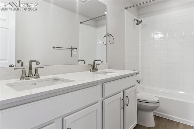 full bathroom featuring vanity, wood-type flooring, tiled shower / bath, and toilet