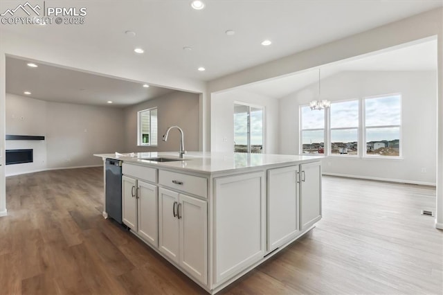 kitchen with white cabinets, dishwasher, sink, and a kitchen island with sink