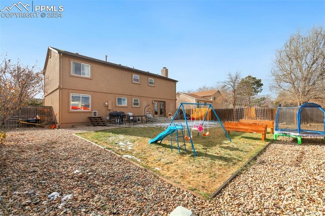 rear view of property with a playground, a patio area, and a trampoline