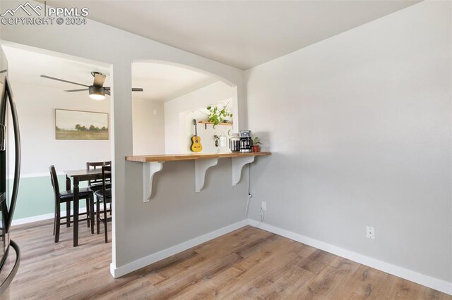 interior space with kitchen peninsula, a kitchen breakfast bar, ceiling fan, light hardwood / wood-style flooring, and stainless steel refrigerator