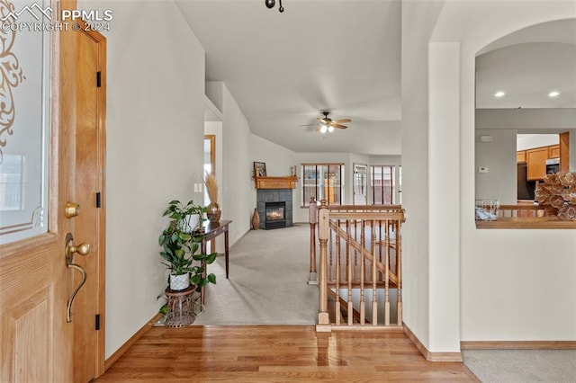 entryway with a tiled fireplace, ceiling fan, and light hardwood / wood-style floors