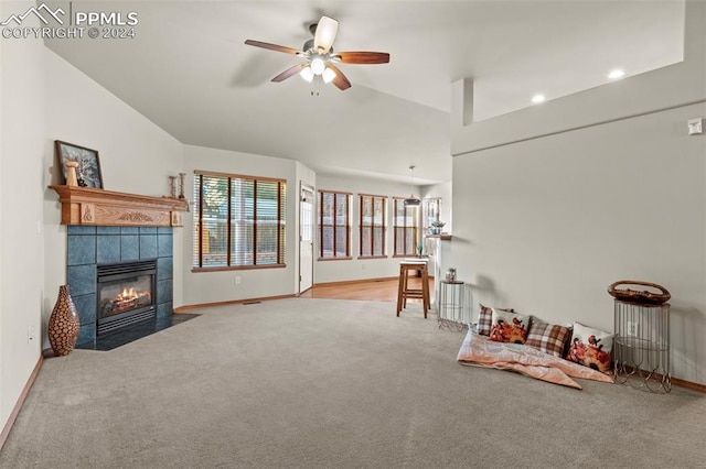 interior space featuring a tile fireplace, ceiling fan, light colored carpet, and lofted ceiling