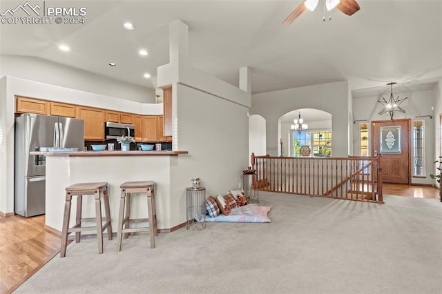 kitchen with pendant lighting, appliances with stainless steel finishes, light hardwood / wood-style floors, a kitchen bar, and kitchen peninsula