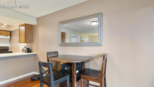 dining space featuring a textured ceiling and hardwood / wood-style flooring