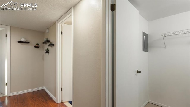 hall with electric panel, wood-type flooring, and a textured ceiling