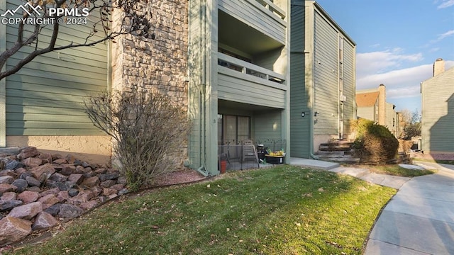 view of side of home with a lawn and a balcony