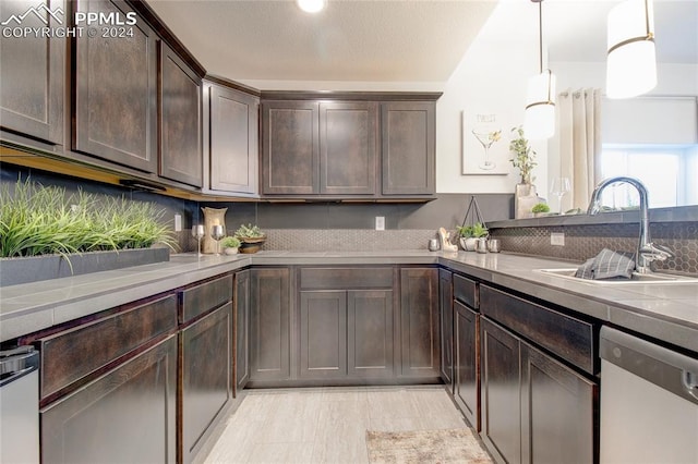 kitchen with dishwasher, backsplash, sink, hanging light fixtures, and dark brown cabinetry