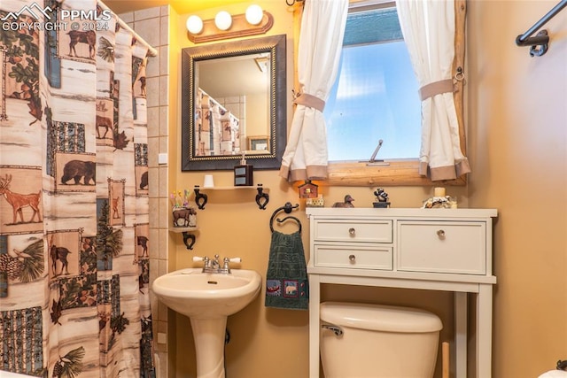 bathroom featuring toilet, walk in shower, and sink