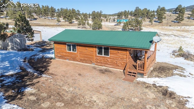 view of snowy exterior featuring a storage shed