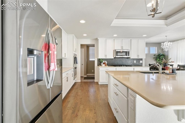 kitchen featuring sink, hanging light fixtures, light hardwood / wood-style floors, white cabinetry, and stainless steel appliances