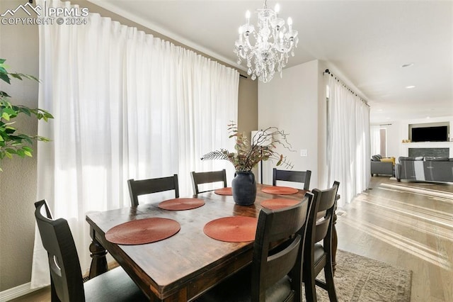 dining room with a fireplace, hardwood / wood-style flooring, and a notable chandelier