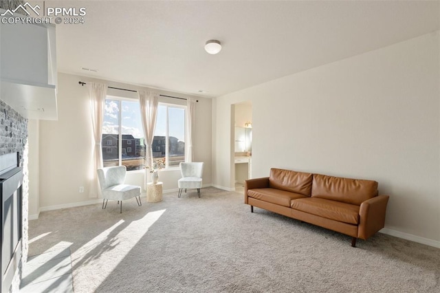 carpeted living room with a stone fireplace