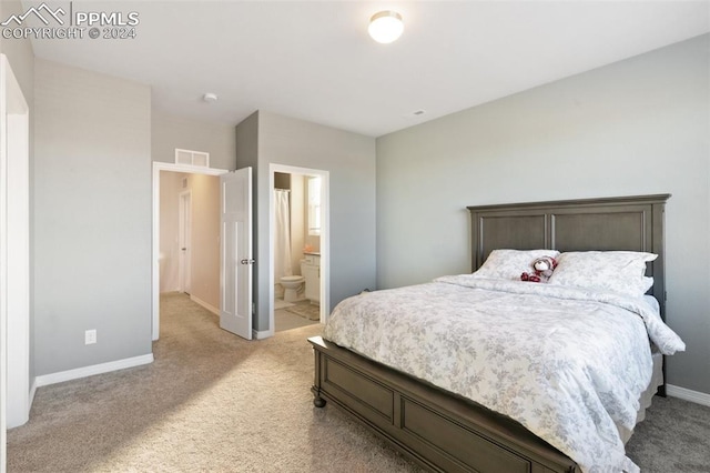 bedroom with ensuite bathroom and light colored carpet