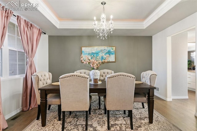 dining area featuring a raised ceiling, light hardwood / wood-style flooring, and a chandelier