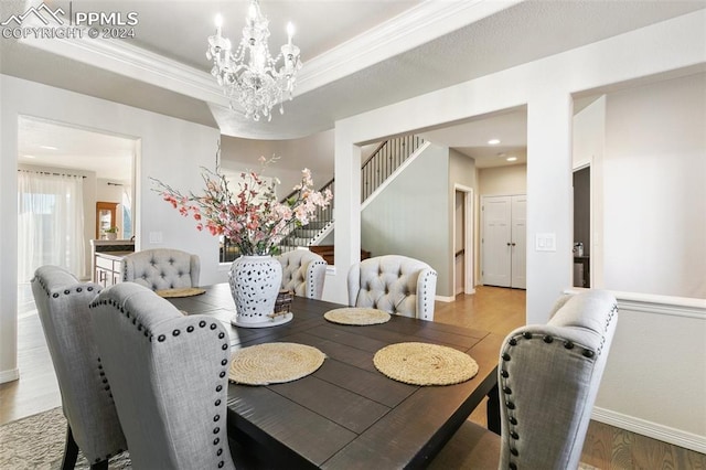 dining space featuring a tray ceiling, an inviting chandelier, wood-type flooring, and ornamental molding