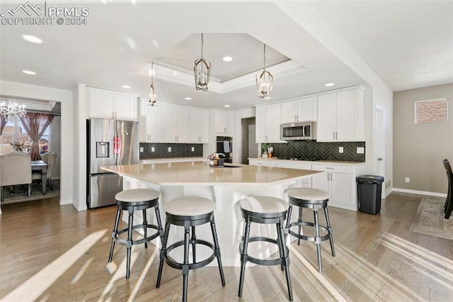 kitchen with a spacious island, white cabinetry, stainless steel appliances, and light wood-type flooring