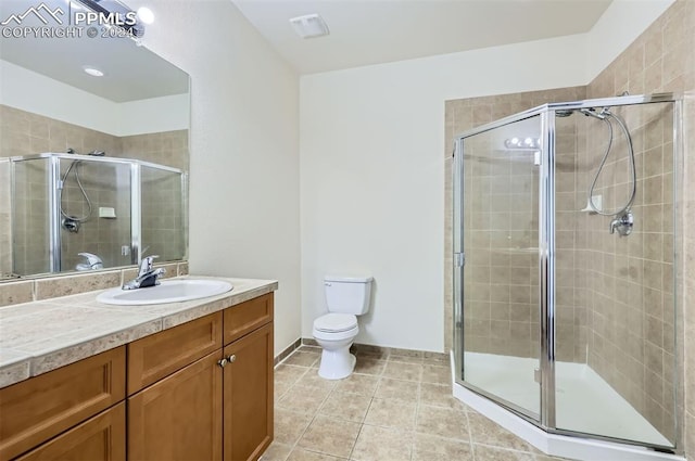 bathroom featuring tile patterned flooring, vanity, a shower with door, and toilet