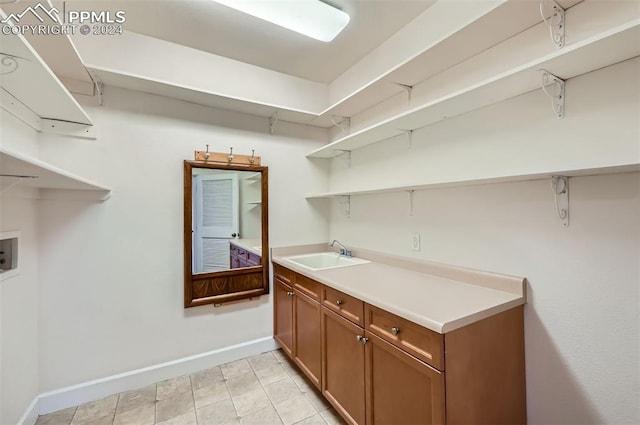 laundry area with cabinets, light tile patterned floors, sink, and hookup for a washing machine