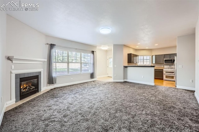 unfurnished living room with light carpet and a tile fireplace