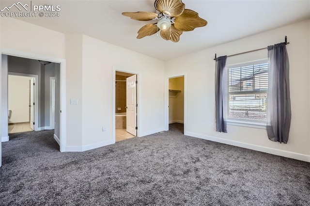 unfurnished bedroom featuring ceiling fan, a spacious closet, connected bathroom, carpet floors, and a closet