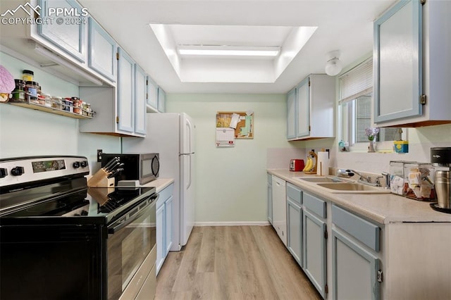 kitchen with electric range, sink, dishwasher, a tray ceiling, and light wood-type flooring