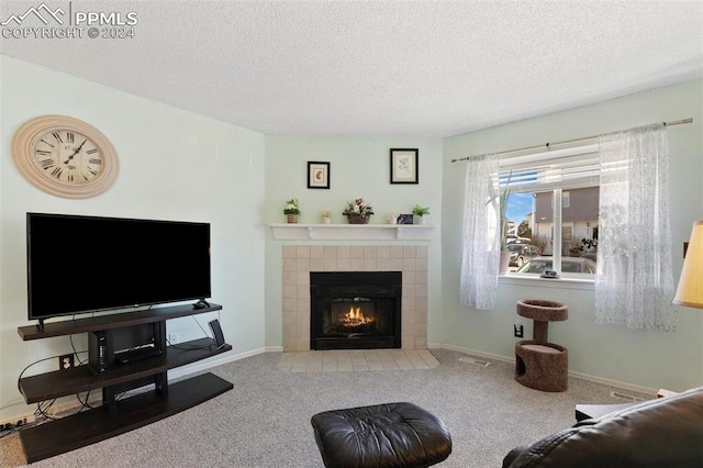 living room with carpet floors, a textured ceiling, and a tiled fireplace