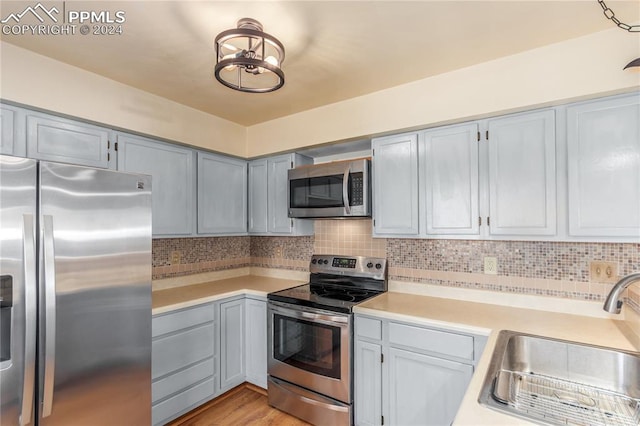 kitchen featuring backsplash, sink, stainless steel appliances, and light hardwood / wood-style floors