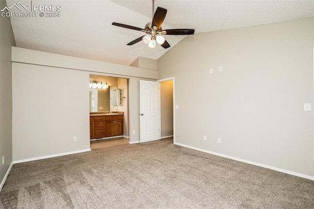 unfurnished bedroom featuring baseboards, ensuite bath, carpet flooring, and vaulted ceiling