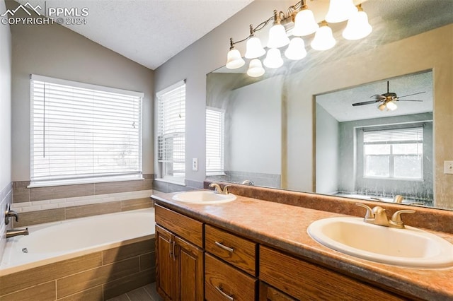 bathroom with a textured ceiling, lofted ceiling, a garden tub, and a sink