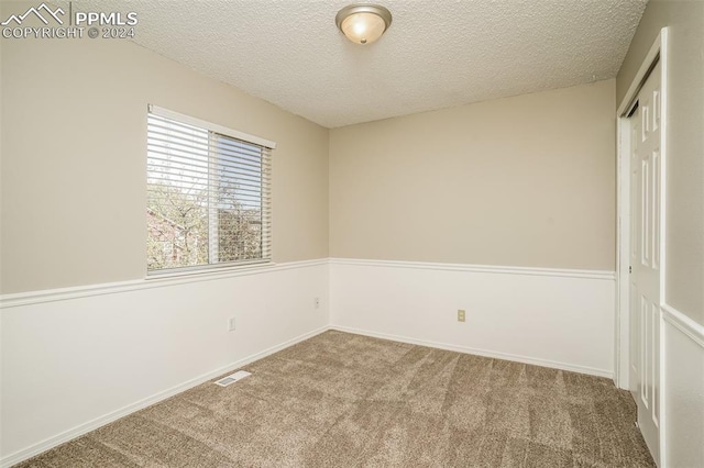 unfurnished room featuring baseboards, visible vents, carpet floors, and a textured ceiling