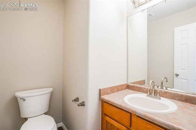 half bath with visible vents, toilet, and vanity