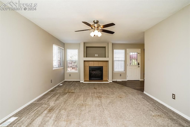 unfurnished living room featuring baseboards, carpet, a ceiling fan, and a tile fireplace