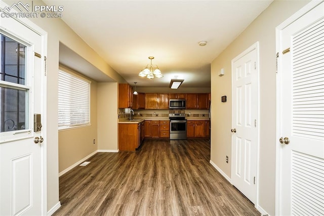 kitchen featuring dark wood finished floors, brown cabinets, stainless steel appliances, and a sink