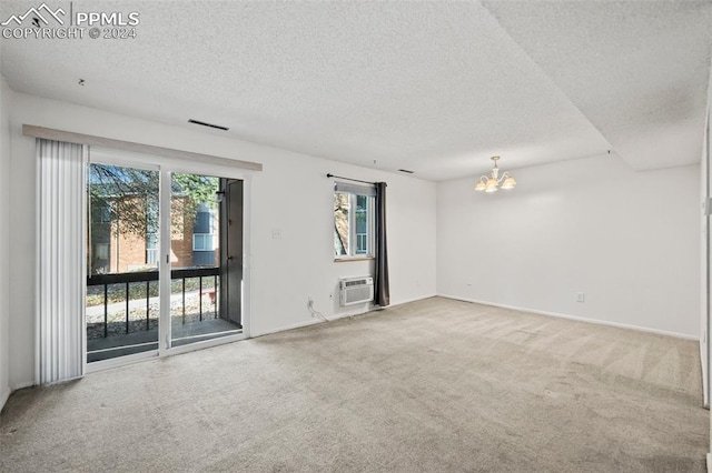 carpeted empty room with a wall mounted air conditioner, a textured ceiling, and an inviting chandelier