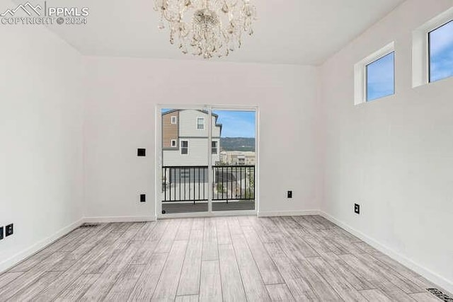 empty room with an inviting chandelier and light wood-type flooring