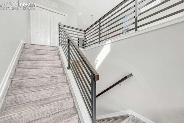 stairway featuring parquet floors and a towering ceiling