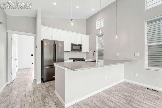 kitchen with high quality fridge, kitchen peninsula, white cabinets, and decorative light fixtures