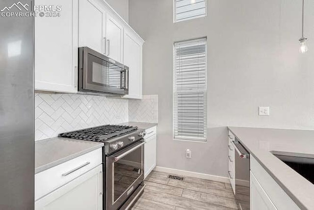 kitchen featuring white cabinetry, backsplash, light hardwood / wood-style flooring, and appliances with stainless steel finishes