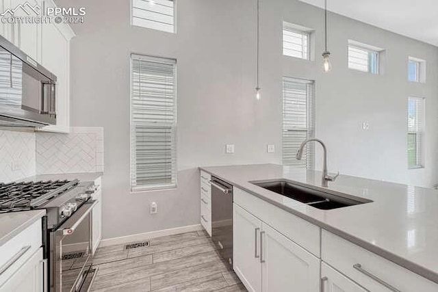 kitchen featuring pendant lighting, sink, white cabinetry, and stainless steel appliances